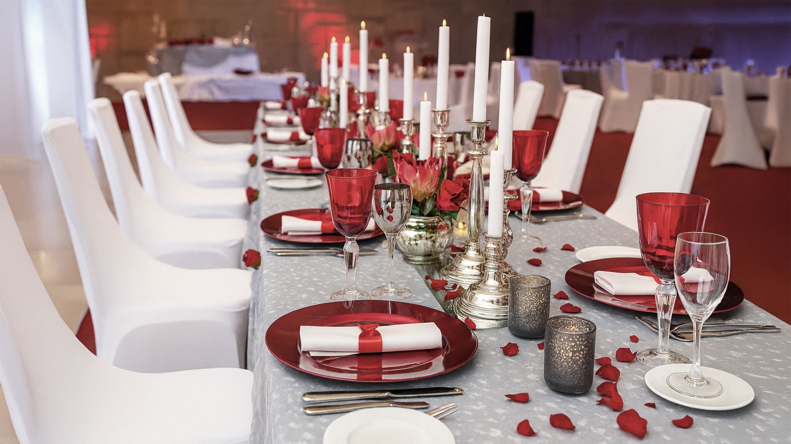 Die perfekte Weihnachtsfeier für Firmen – Location & Tischdeko-Tipps für ein festliches Ambiente Festlich gedeckter Tisch mit roten Akzenten, Kerzen und Rosen – elegante Tischdekoration für Firmen-Weihnachtsfeiern mit Event-DJ Tom Hendrics